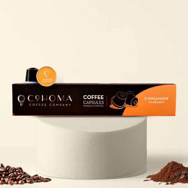 Cohoma Cinnamon Hazelnut Coffee Capsules box displayed with a single capsule placed on top, showcasing the sleek packaging and branding.