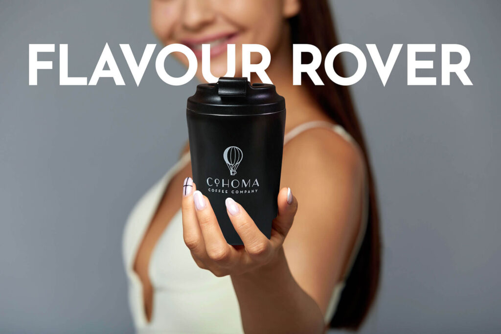 Woman holding a Cohoma Coffee hot tumblr in focus with ‘Flavour Rover’ text in the background