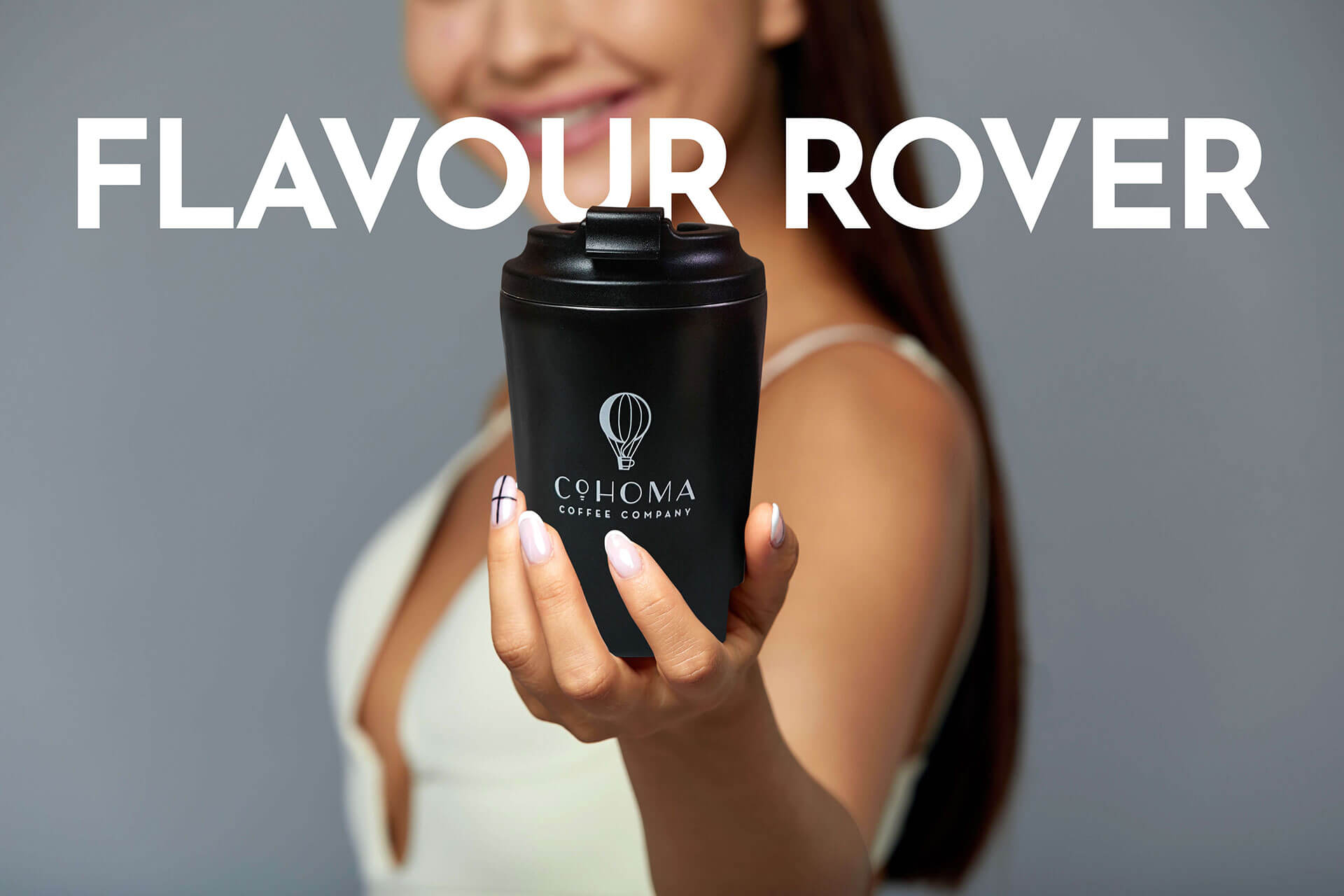 Woman holding a Cohoma Coffee hot tumblr in focus with ‘Flavour Rover’ text in the background