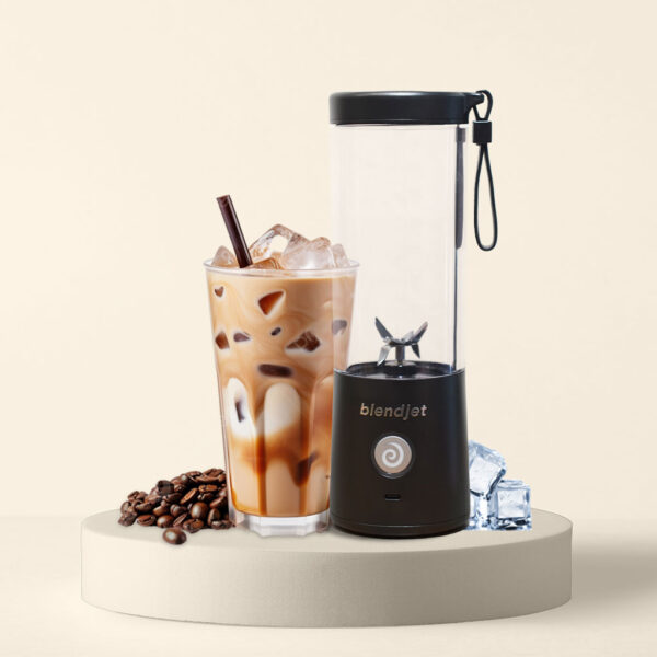 BlendJet portable blender next to a glass of iced coffee, coffee beans, and ice cubes.